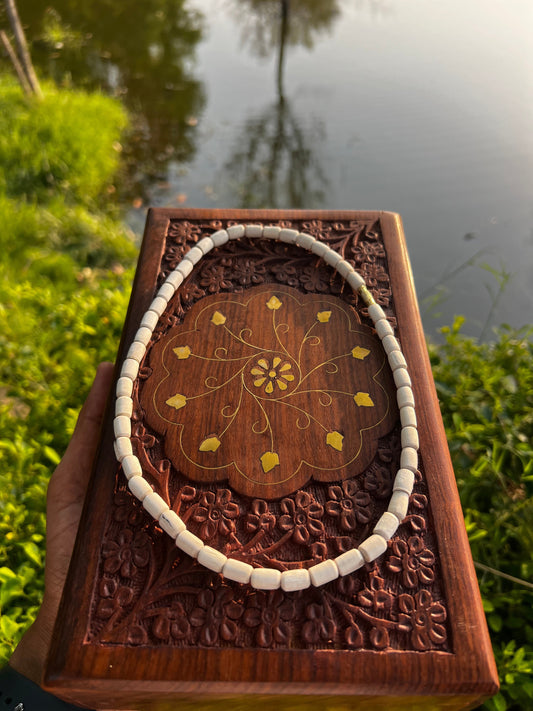 Barrel-bead tulsi mala arranged on a brass-inlaid carved wooden box