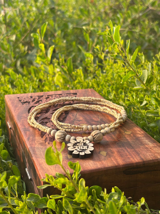 Tulsi mala with Shri Radha flower locket on a carved wooden box among tulsi leaves