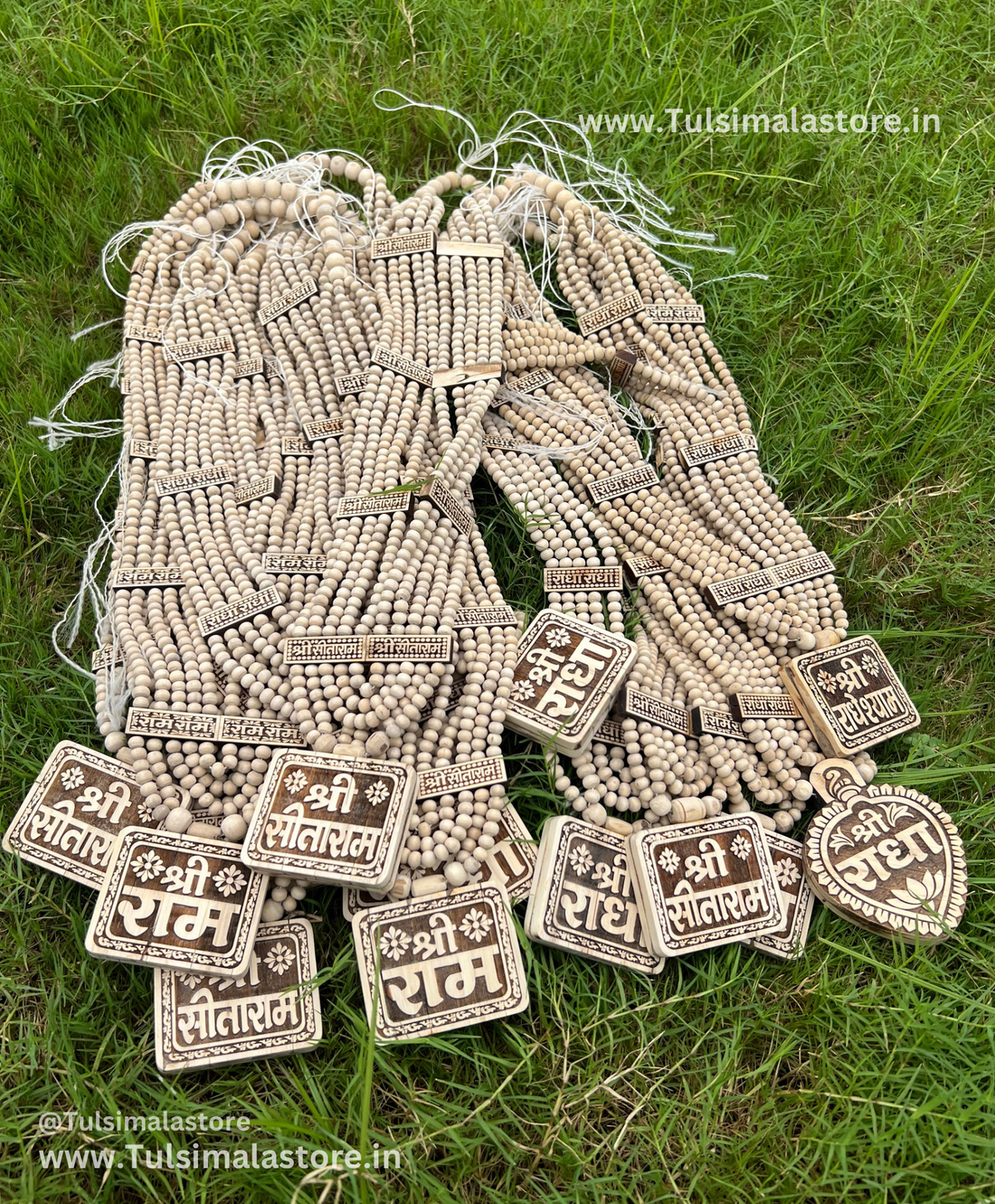 Bundles of tulsi kanthi malas with Ram, Sitaram and Radha name lockets on grass