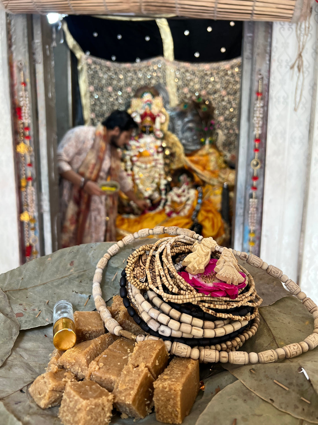 Tulsi malas and prasad offered before a decorated deity in a Vrindavan temple