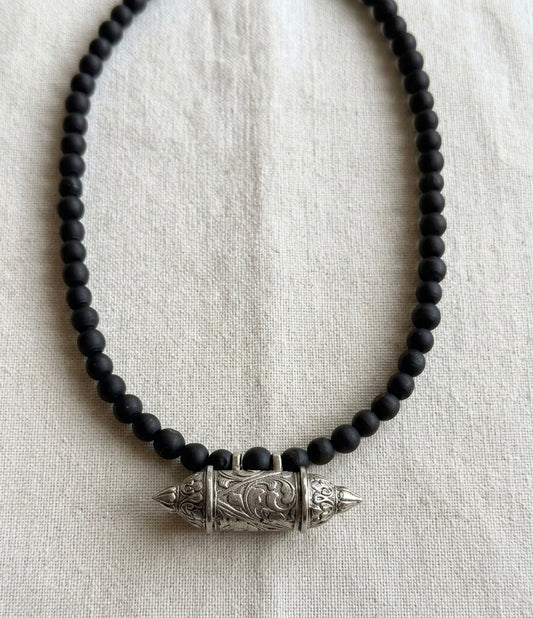 Black round tulsi bead Bhaktamal kavach kanthi mala laid in a loop on a white cloth
