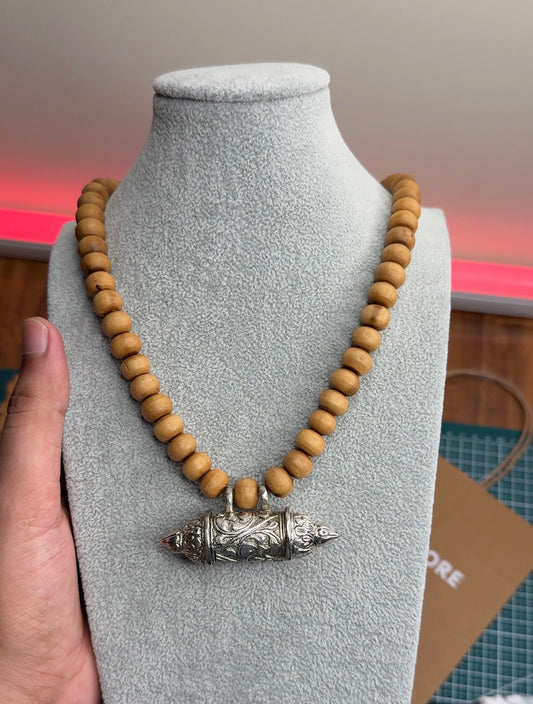 Brown round tulsi bead Bhaktamal kavach kanthi mala held up on a bust at the Tulsimalastore counter
